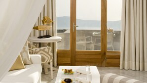 Una habitación moderna y luminosa con candelabro, un comedor con mesa y sillas, y vistas a través de un ventanal.
