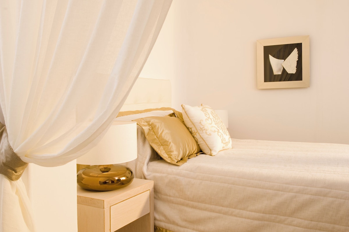 Une chambre à coucher avec un lit, une table de chevet, une lampe et un tableau accroché au mur.