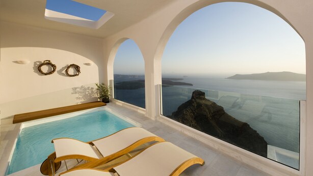 Una piscina interior moderna con vistas despejadas al mar y al paisaje rocoso.