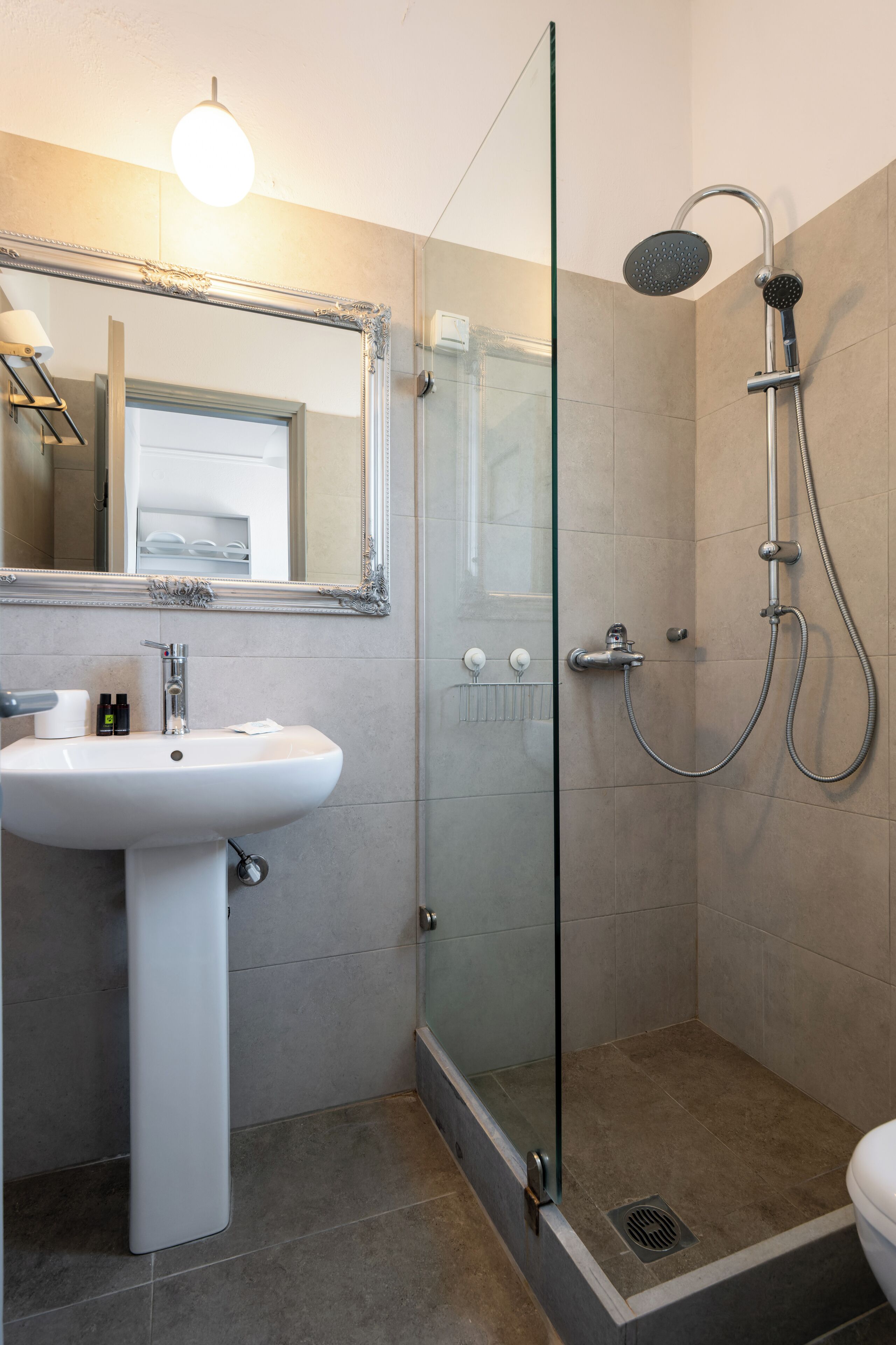 A modern bathroom with a glass shower enclosure, a white sink, and a large mirror.