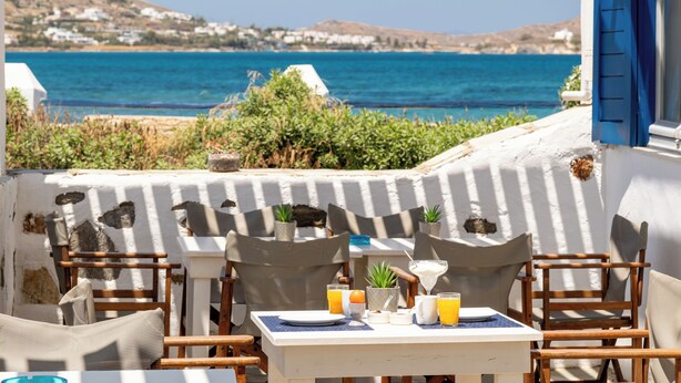 A seaside dining area with a table set for two, overlooking the sea. - Naoussa Hotel Paros by Booking Kottas (Paros)