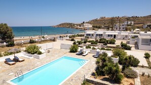 A pool area with lounge chairs and a clear view of the sea. - Naoussa Hotel Paros by Booking Kottas (Paros)