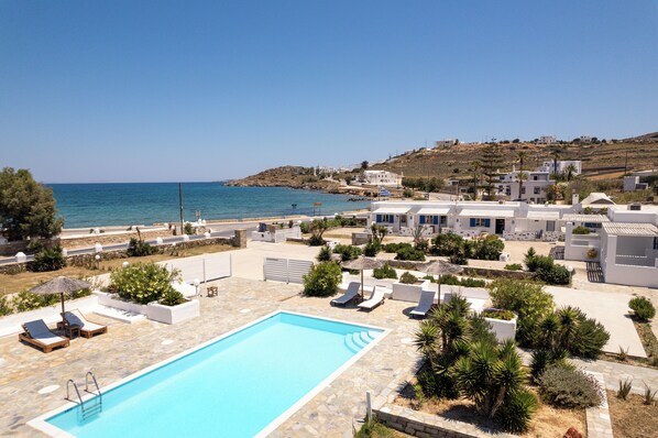A pool area with lounge chairs and a clear view of the sea.