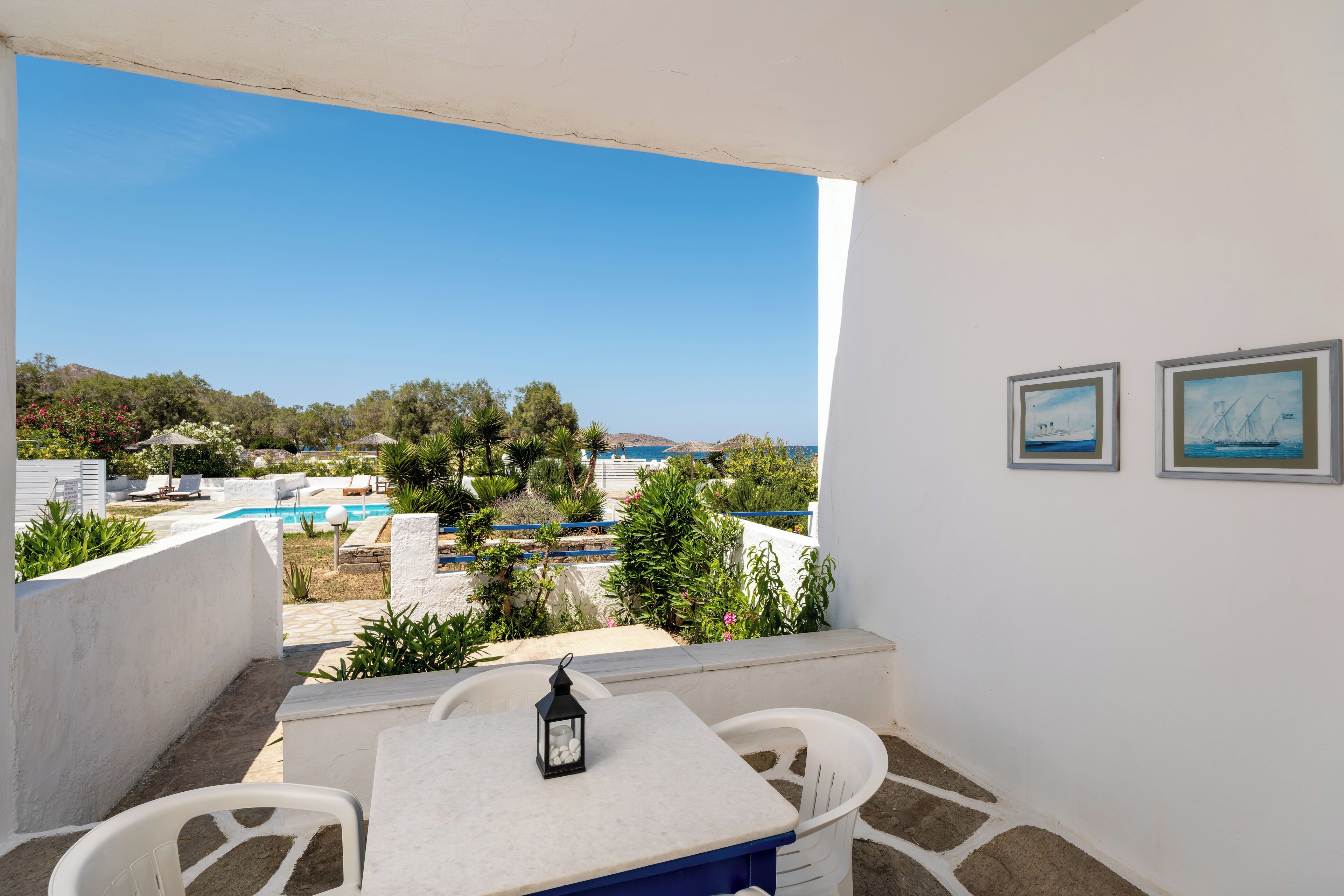 Varanda com mesa e cadeiras, vista para uma piscina e vegetação.