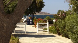A pathway leading to a gate with a view of the sea and a mountain in the distance. - Naoussa Hotel Paros by Booking Kottas (Paros)