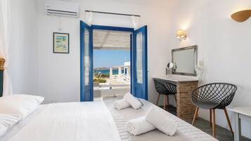 A hotel room with a bed, a desk, a chair, and a view of the beach.
