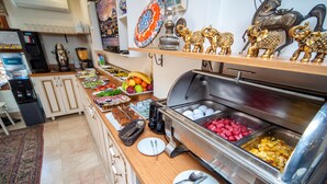 Ein reichhaltiges Buffet mit verschiedenen Speisen, einer Kaffeemaschine und dekorativen Gegenständen auf Regalen.