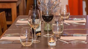 Une table à manger dressée avec des verres à vin, une bouteille et une bougie.