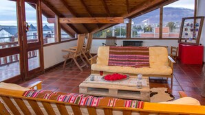 Un balcon spacieux agrémenté de meubles en bois, d’un canapé et d’une table sur laquelle sont posés une assiette décorative et un verre.