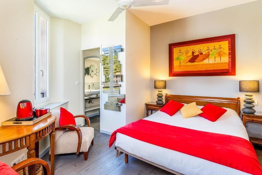 Ein Hotelzimmer mit Bett, Schreibtisch, Stuhl, Fenster und einem Bild an der Wand.