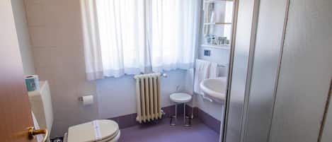 Un baño con inodoro, bidé y un lavamanos pequeño.