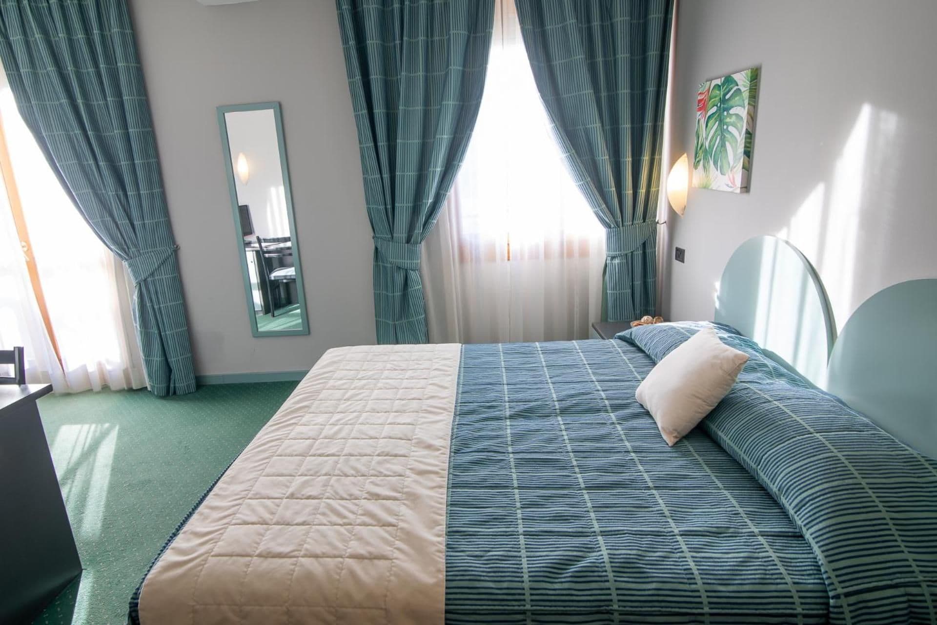 A hotel room with a bed, a desk, and a chair.
