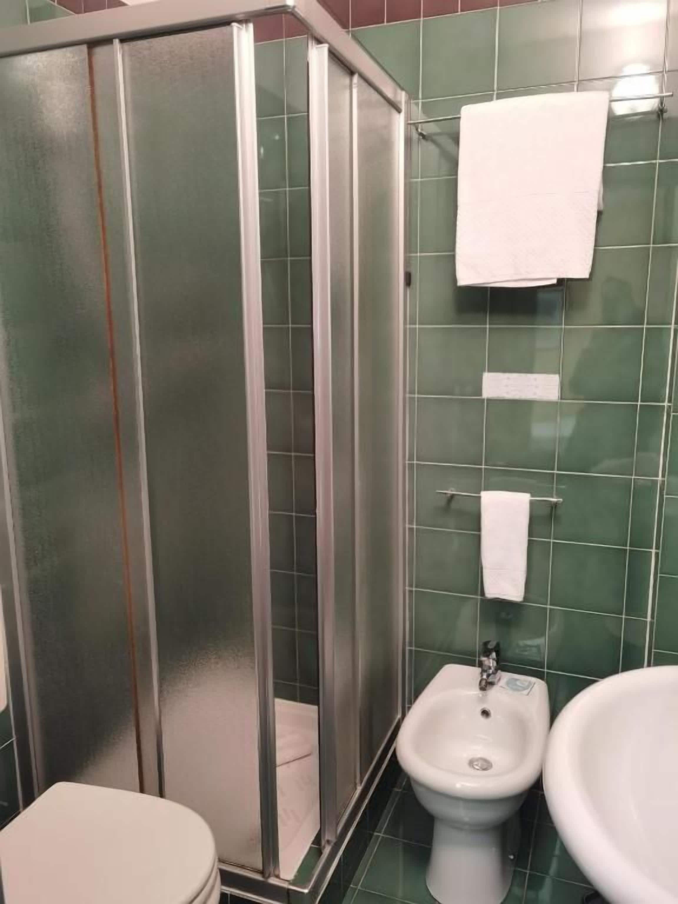 Une salle de bain comprenant un espace douche, des toilettes, un bidet et un lavabo.