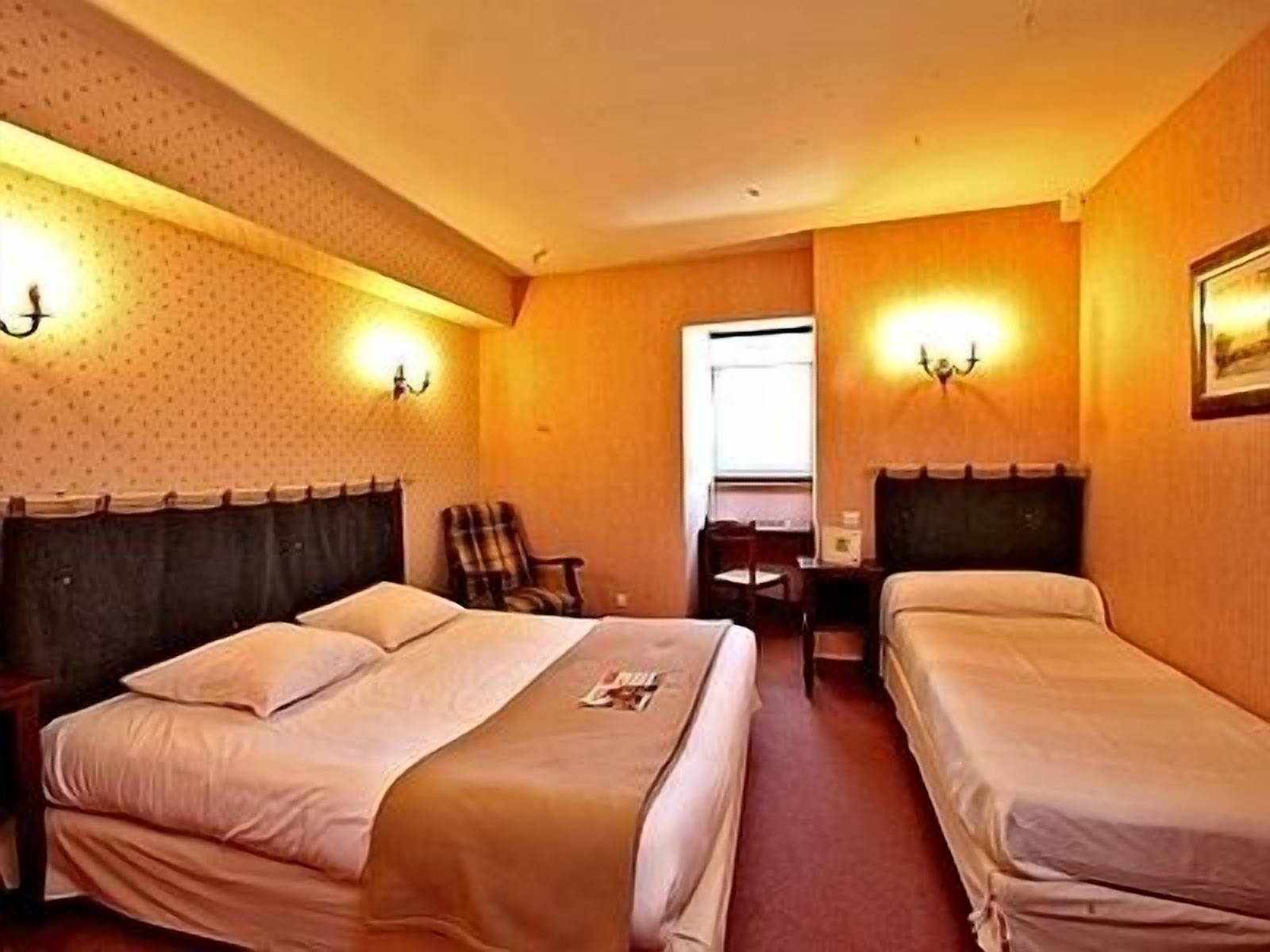 Une chambre d’hôtel avec deux lits, un bureau et deux chaises.