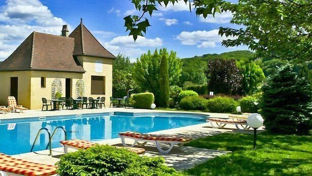 Una casa con piscina, rodeada de vegetación y una colina al fondo.