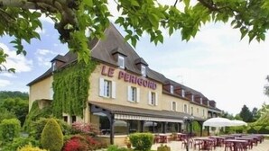 Un edificio llamado "LE PERIGORD" con un espacio de estar al aire libre cubierto y un jardín.