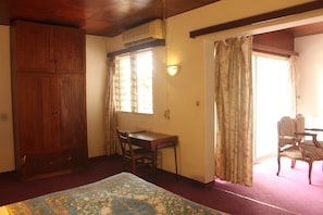 A room with a bed, a wooden wardrobe, a desk with a chair, and a window with curtains. - Central Hotel (Yaoundé)
