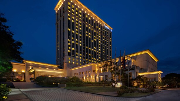 A high-rise hotel with a modern design, featuring a prominent 'Radisson' sign, a well-lit entrance, and a landscaped front garden. - Radisson Blu Cebu (Cebu City)