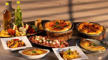 A variety of dishes including pizza, pasta, and charcuterie on a wooden table.