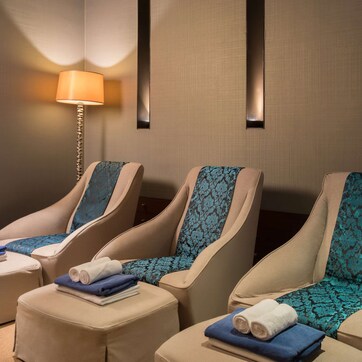 A spa room with three massage chairs, each with a towel and a blue-patterned cushion.
