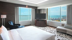 A hotel room with a large bed, a sofa, a TV, and a view of the sea. - Radisson Blu Cebu (Cebu City)
