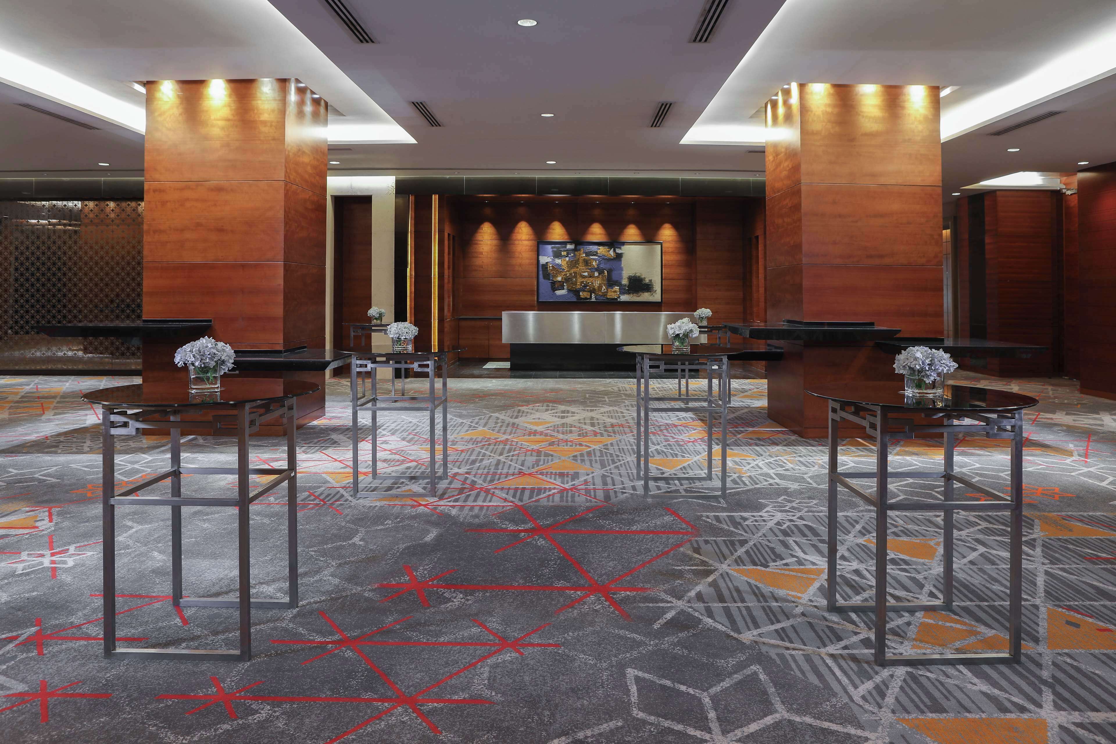 Un hall de hotel con mostrador de recepción, cuatro zonas de estar y una alfombra estampada.