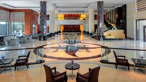 A spacious lobby with a central circular seating area, a reception desk, and a staircase leading to upper floors. - Radisson Blu Cebu (Cebu City)