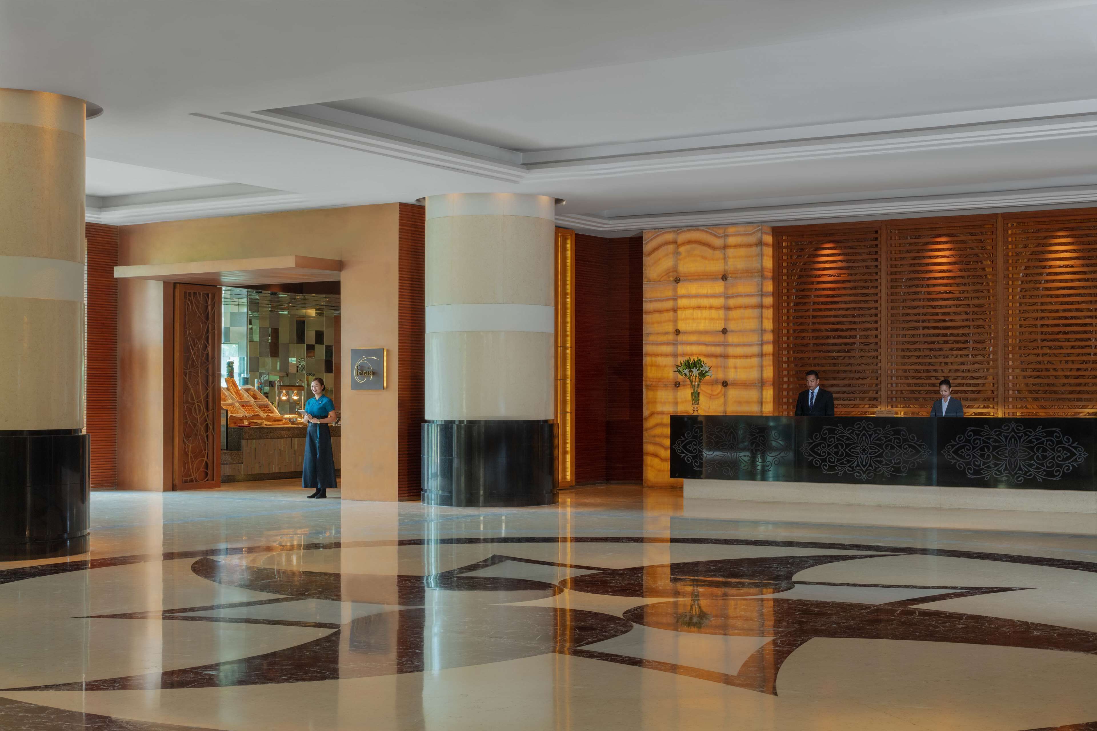 A spacious lobby with a polished marble floor, a reception desk, and a receptionist.