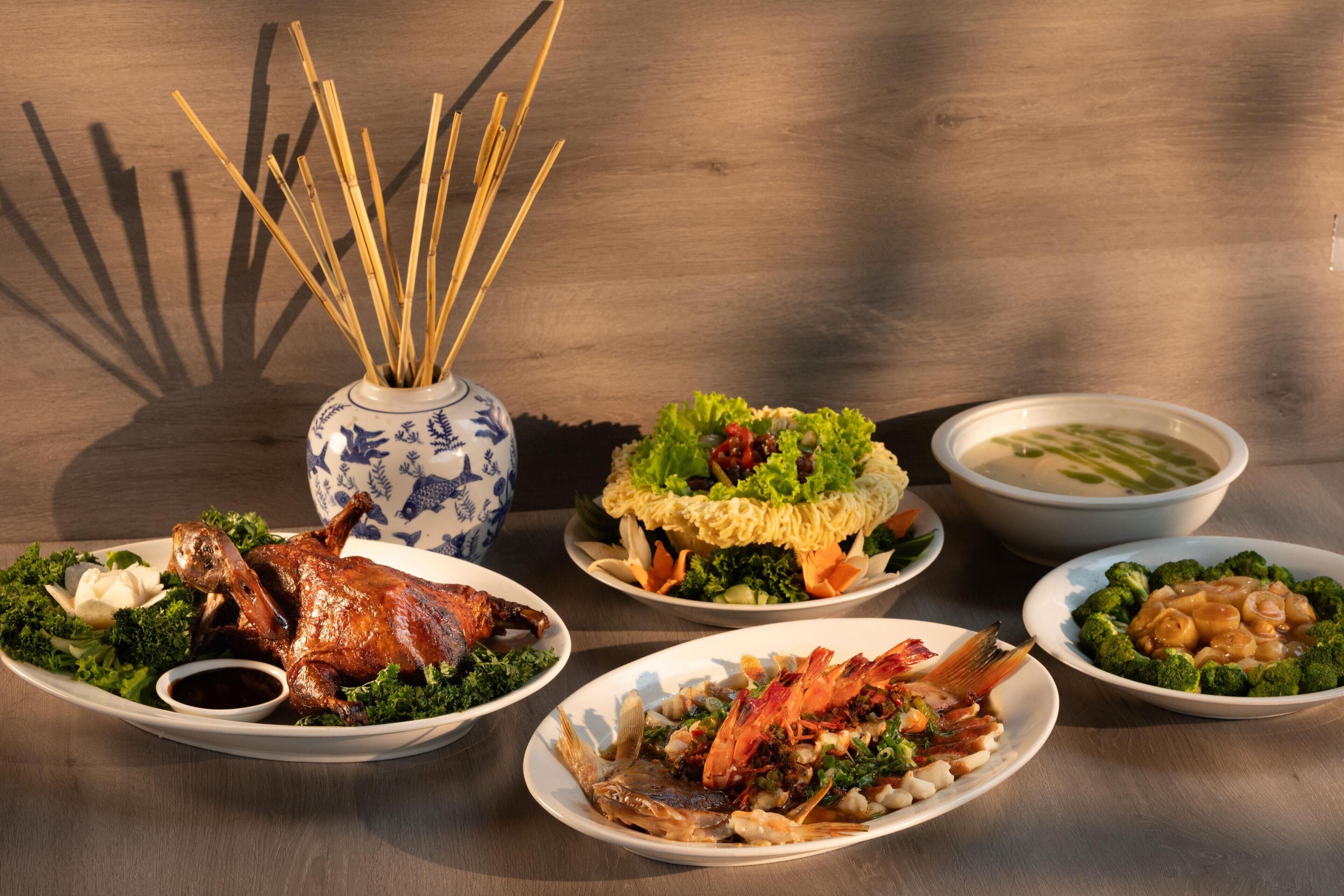 Una mesa con diversos platos, incluyendo un pato asado, mariscos y verduras.