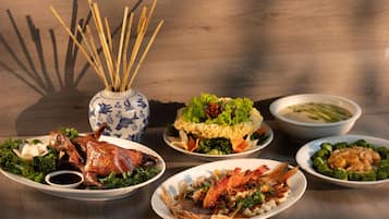 A table with various dishes including a roasted duck, seafood, and vegetables.
