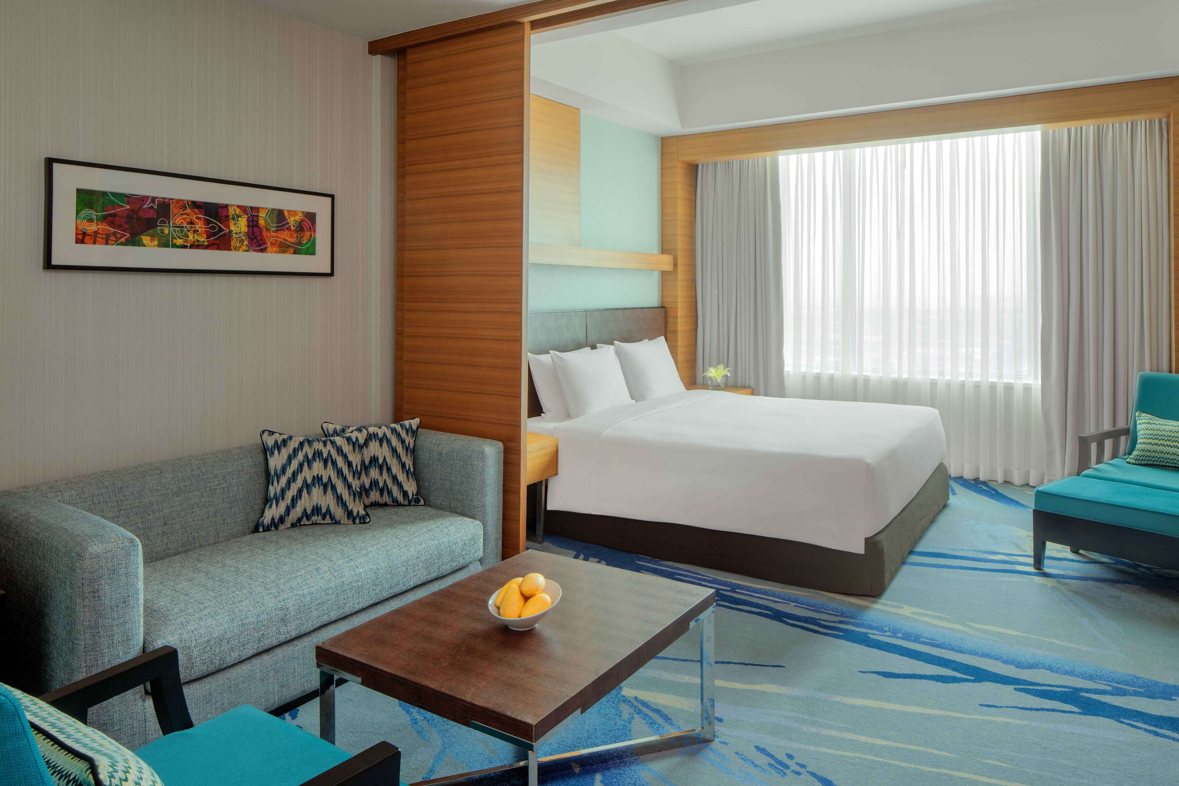 Una habitación de hotel con cama, sofá, mesa de centro y un cuadro en la pared.