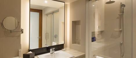 A modern bathroom with a large mirror, a sink, a glass-enclosed shower, and a towel rack.