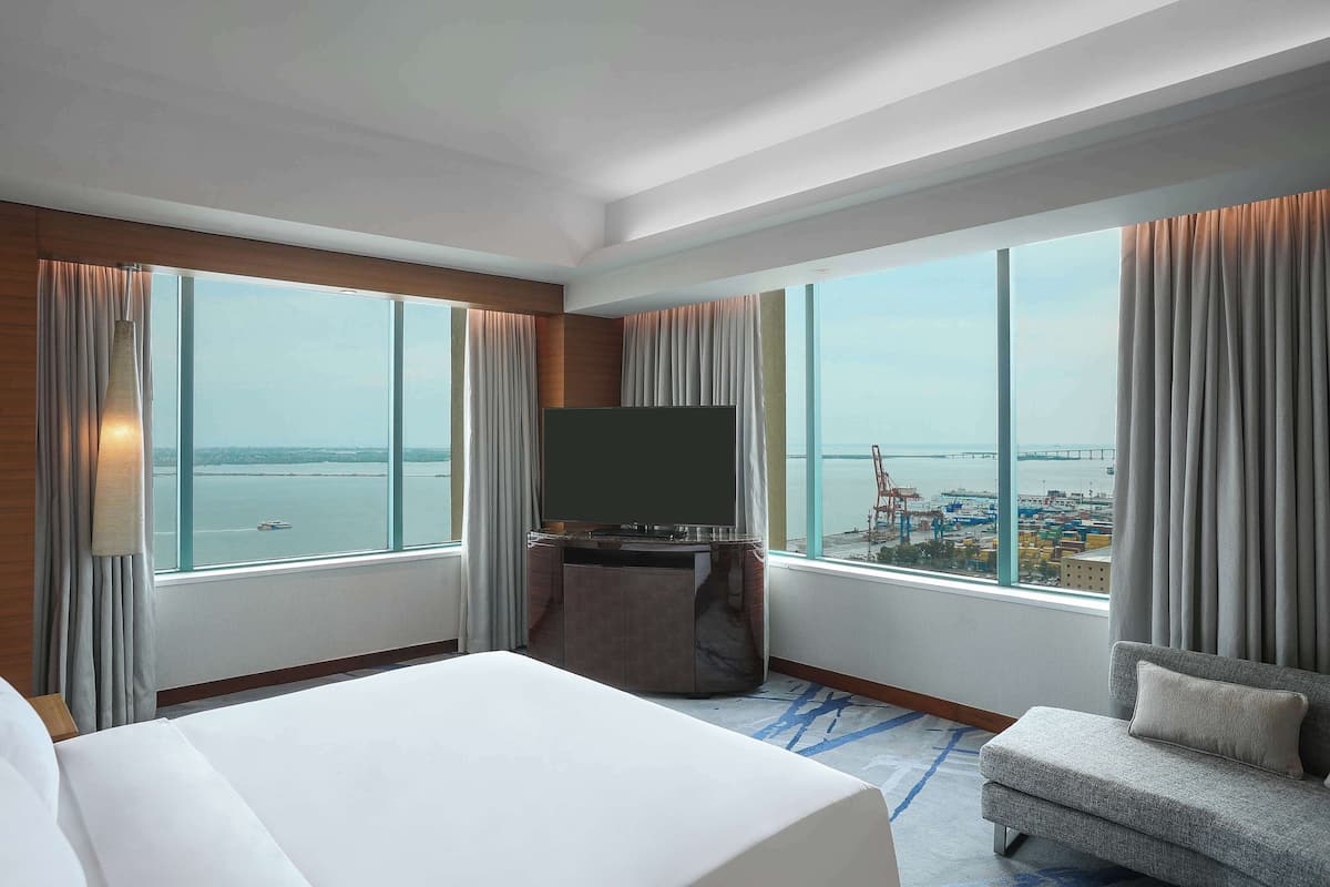 A hotel room with a large bed, a TV, and a sofa.