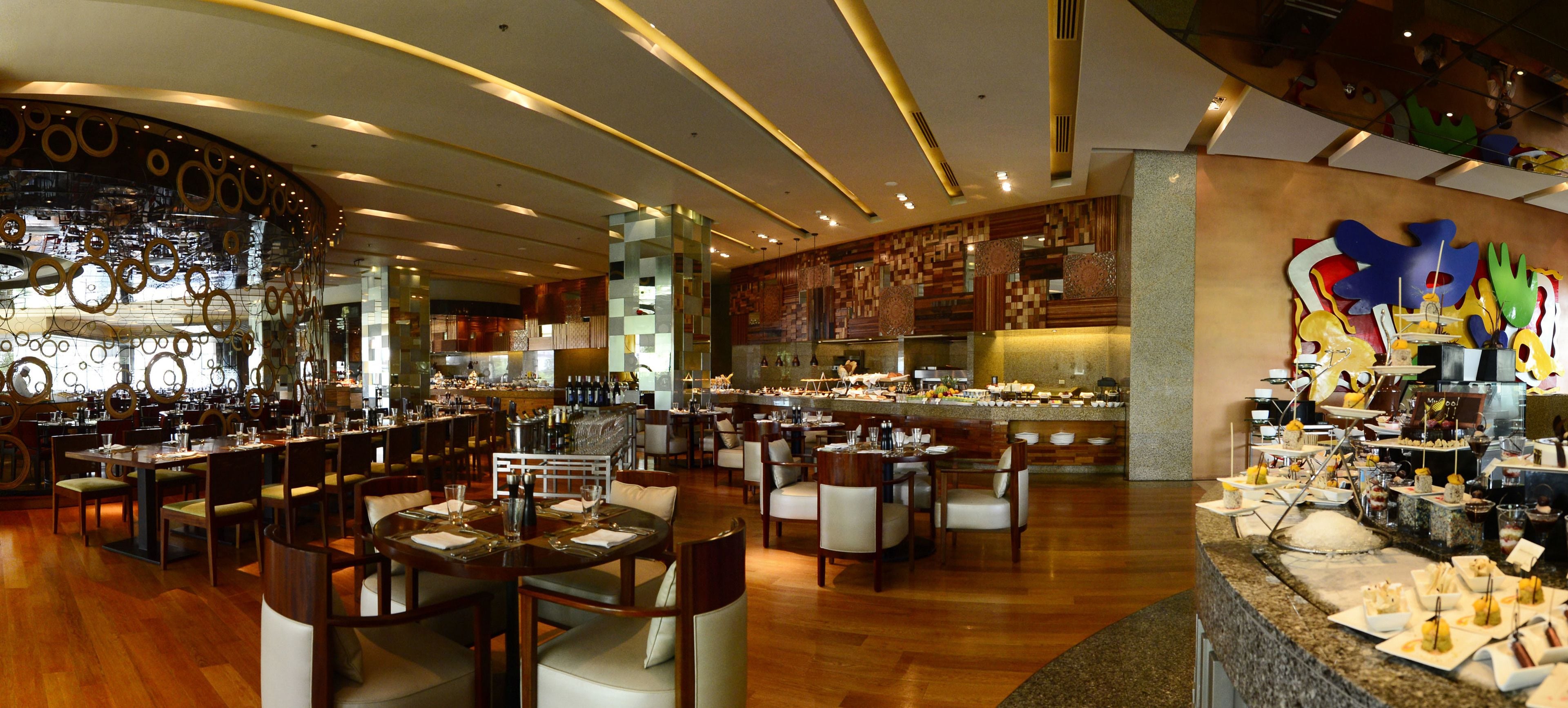 Un restaurante espacioso con varias zonas de comedor, una barra central y un bufé.