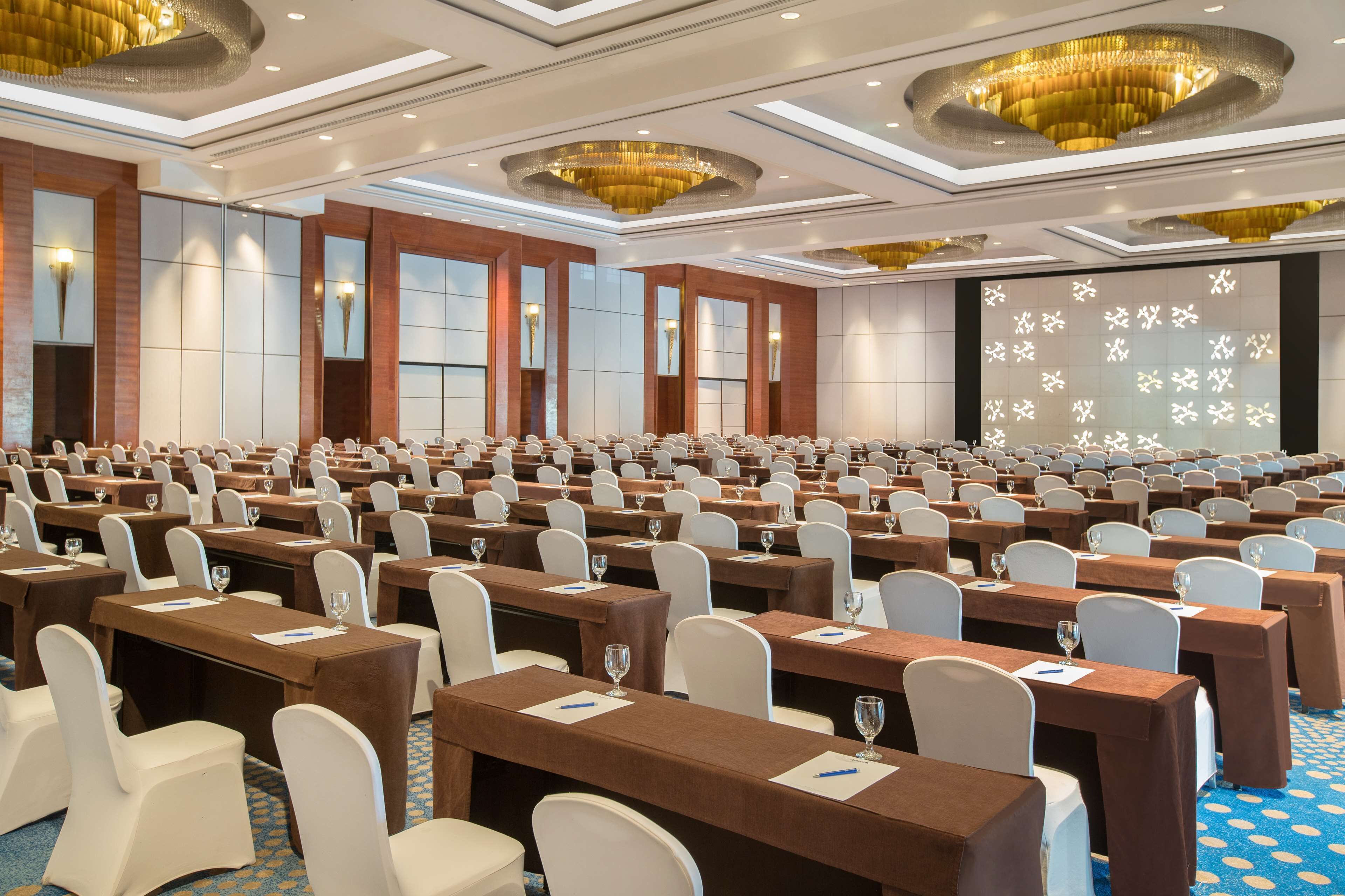 A large conference room with rows of tables and chairs, equipped with name cards and water glasses.