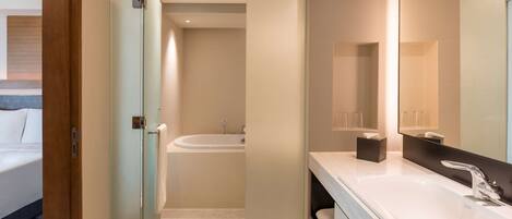 A modern bathroom with a glass shower enclosure, a bathtub, and a large mirror.