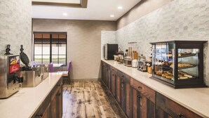 Una cocina moderna con una plancha para gofres, estación de café y una vitrina con pastelería.