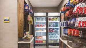 Zona de venta automática de aperitivos y bebidas, con dos refrigeradores llenos de productos variados.