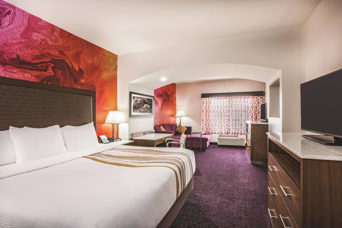 Une chambre d’hôtel avec un grand lit, un bureau, un canapé et une télévision.