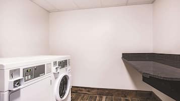 Un cuarto de lavandería con lavadora de carga frontal, piso de madera y encimera oscura.