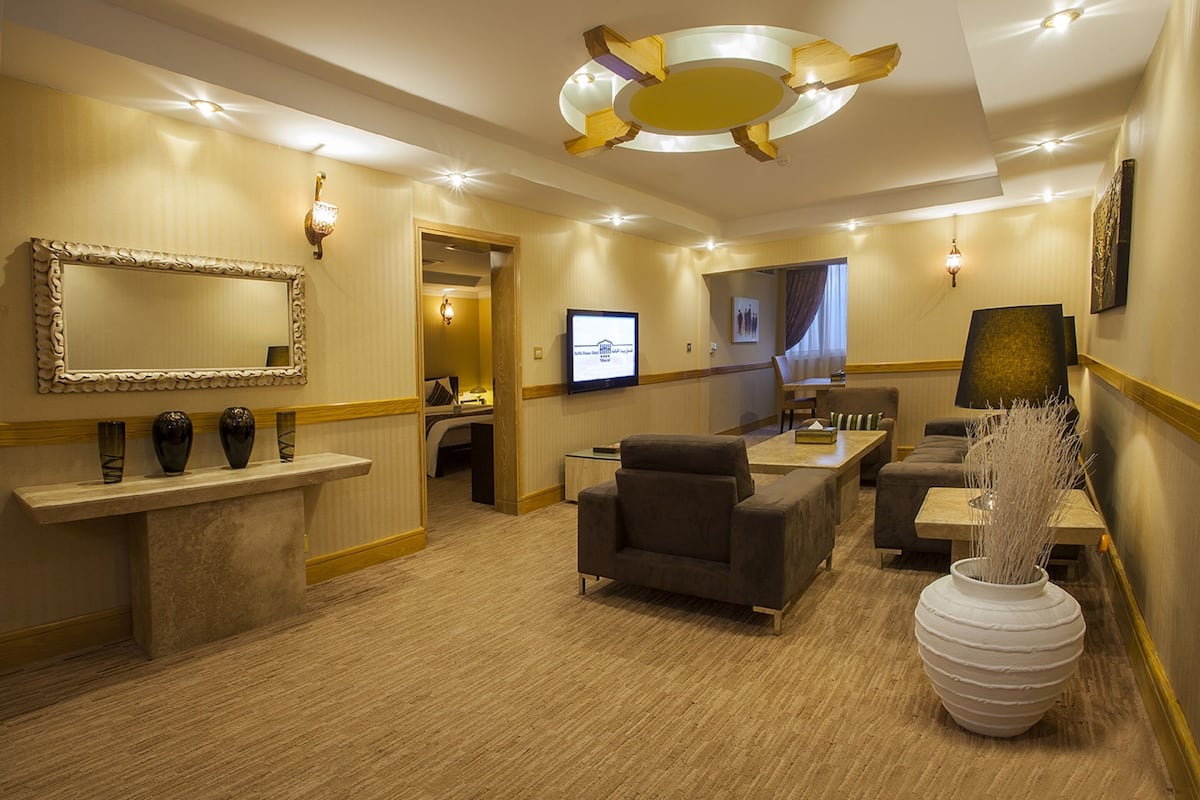 A hotel lobby with a reception desk, seating area, and a large mirror.