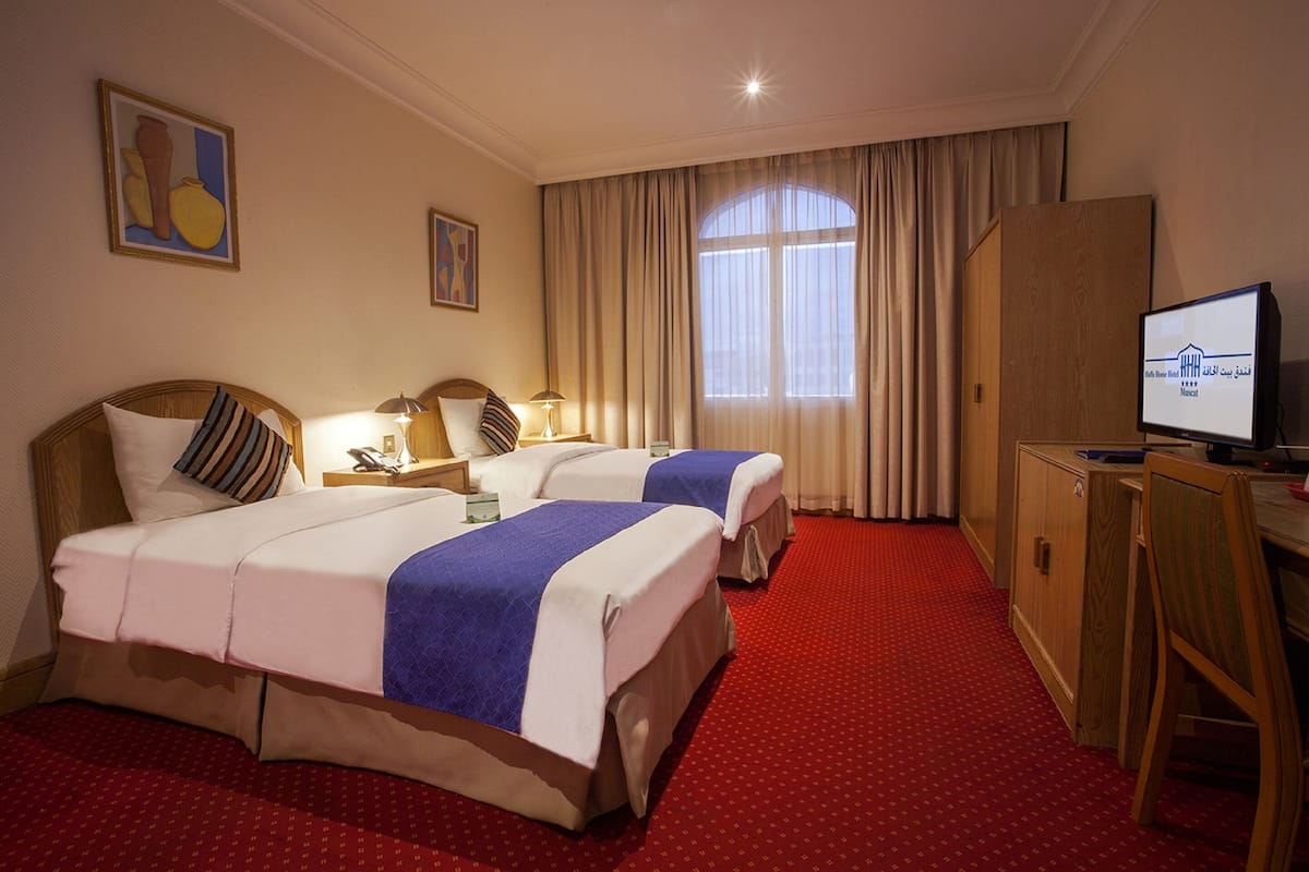A hotel room with two beds, a desk, a television, and a wardrobe.
