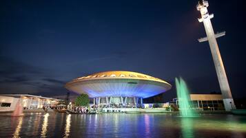 A large, modern building with a distinctive dome-shaped roof and a tall, slender tower.
