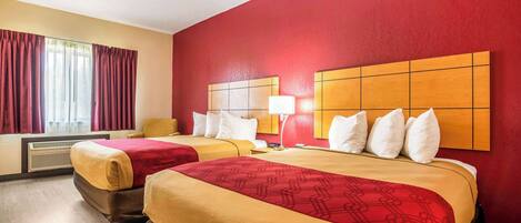 A hotel room with two beds, red walls, and a large window with curtains.