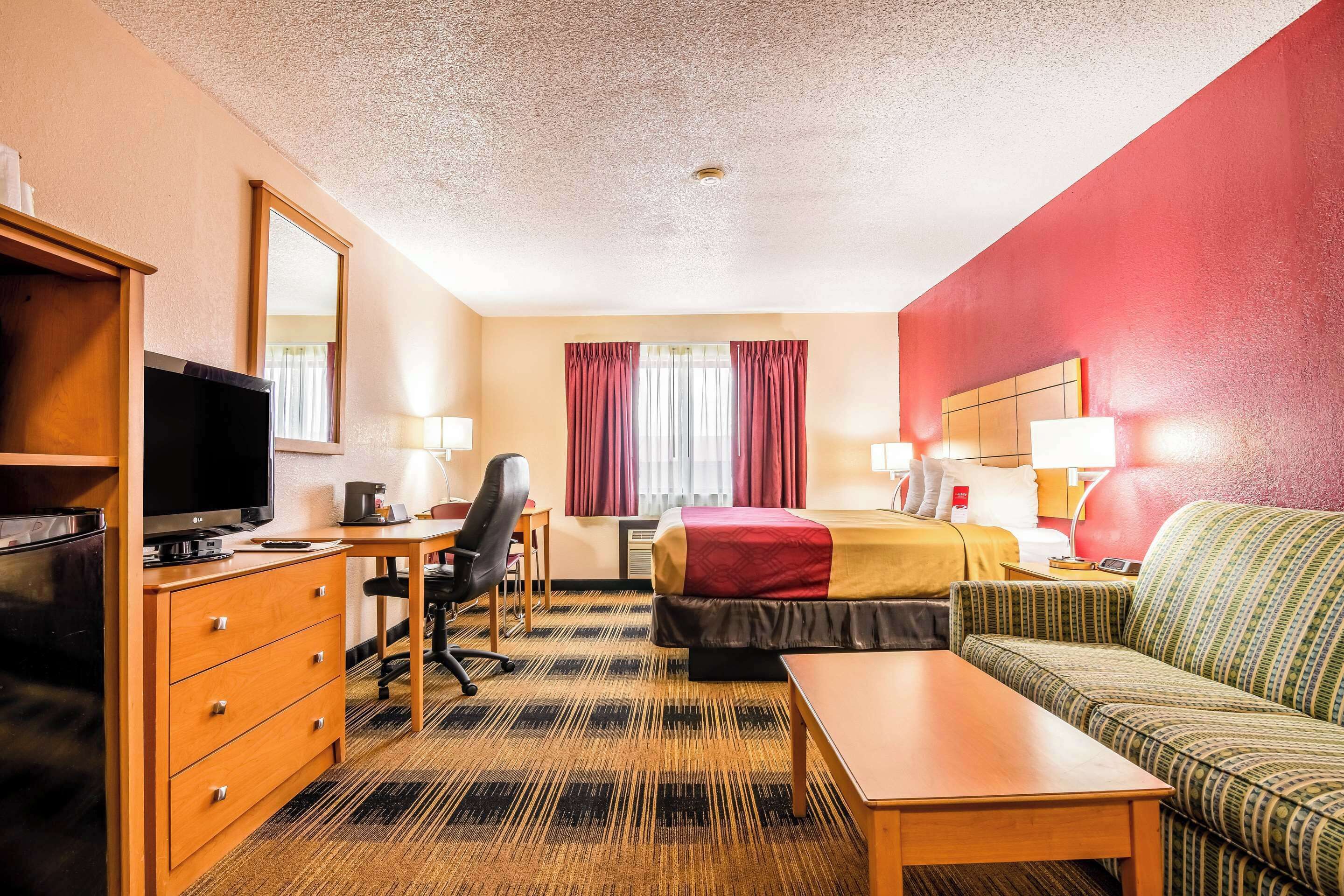 Ein Hotelzimmer mit Bett, Schreibtisch mit Computer, Fernseher, Sofa und Couchtisch.