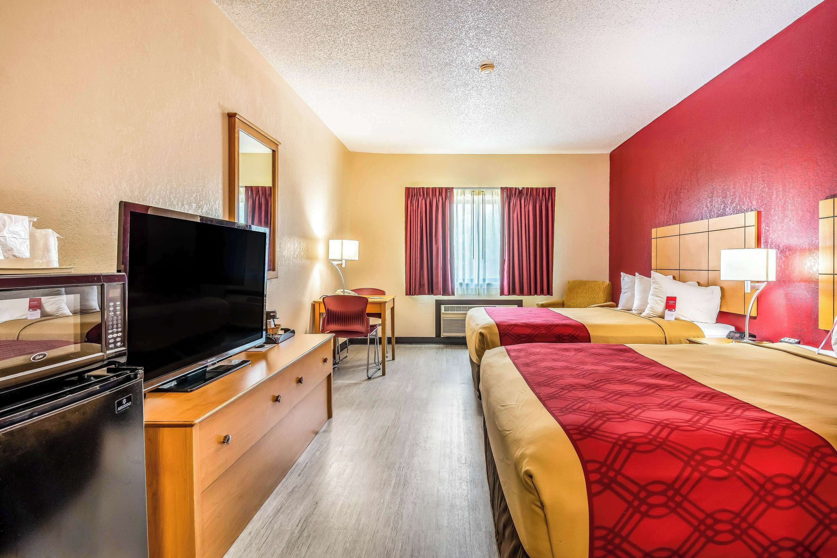 Une chambre d’hôtel équipée d’une télévision, d’un bureau, d’une chaise, de deux lits et d’un mini-bar.