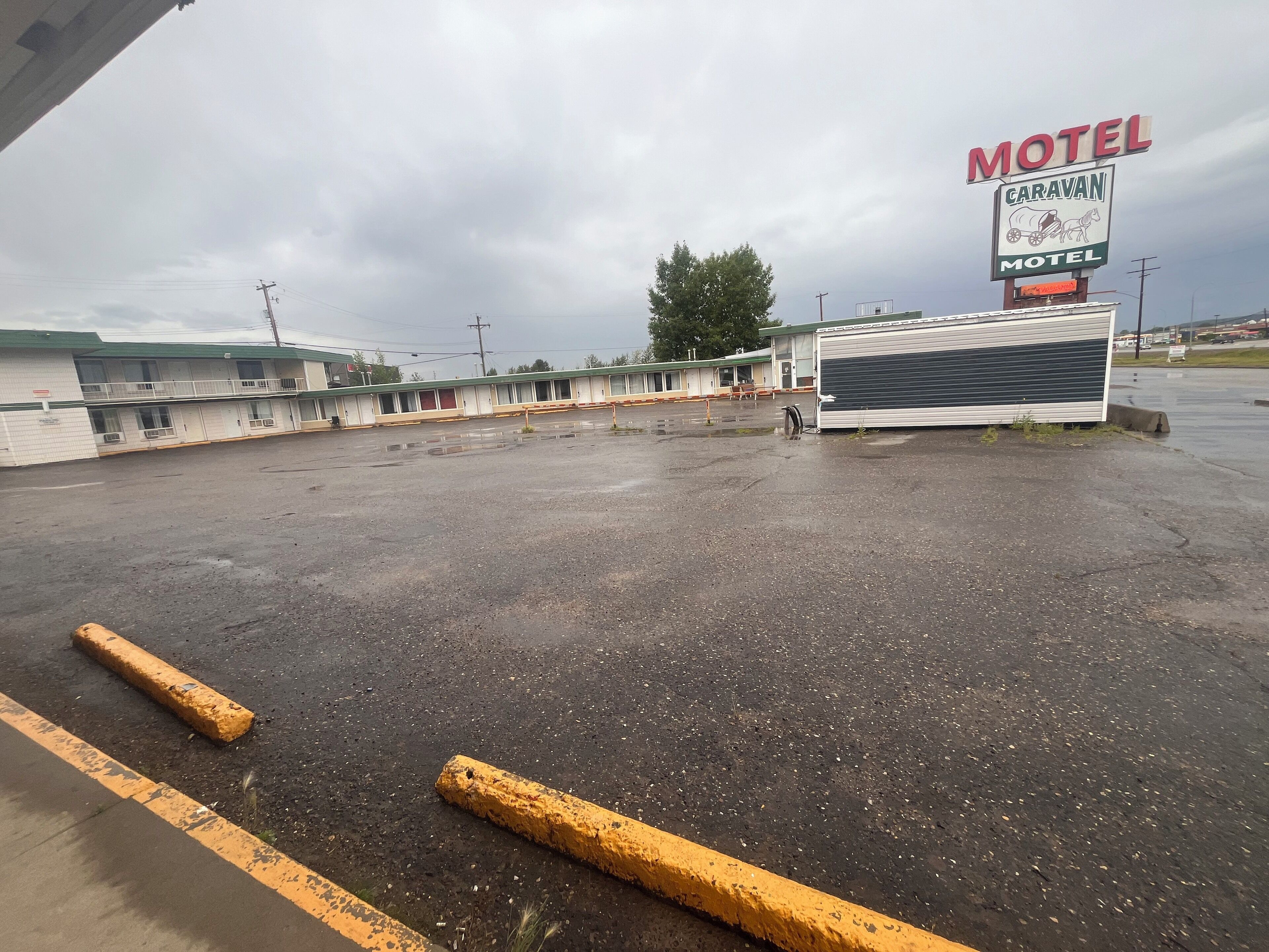 A motel with multiple units, a large sign advertising the motel, and a parking lot with yellow curbs.