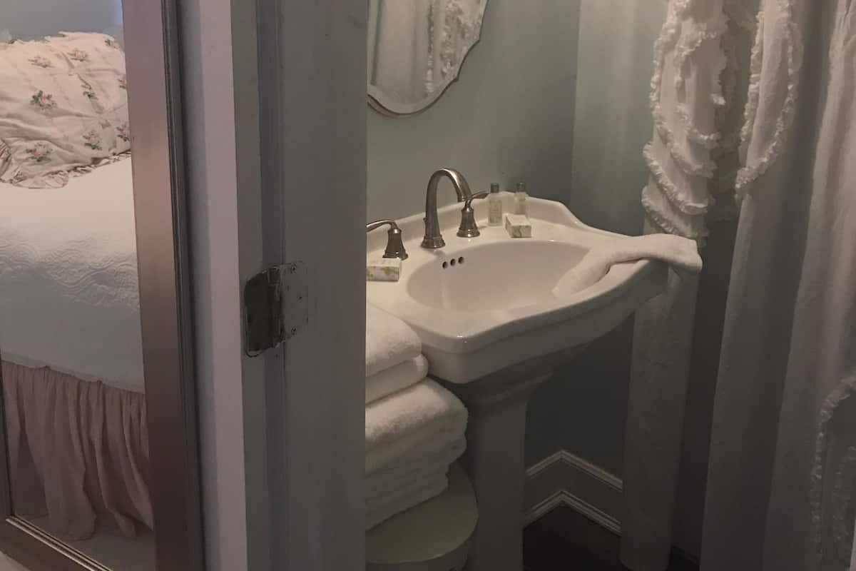 A bathroom with a sink, mirror, and towel rack.