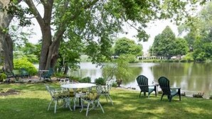 Une terrasse au bord du lac, avec une table et des chaises, entourée d’arbres et offrant une vue sur le lac.