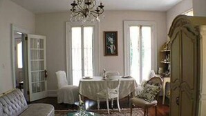Un salon comprenant un canapé, une table basse en verre, une table à manger avec des chaises, un lustre et un buffet.